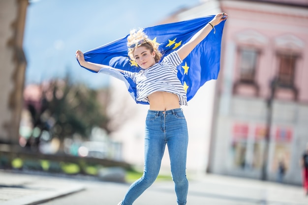 Attraktives glückliches junges Mädchen mit der Flagge der Europäischen Union.