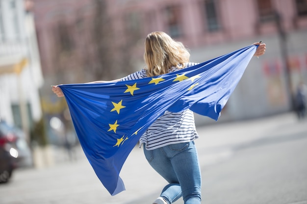 Attraktives glückliches junges Mädchen mit der Flagge der Europäischen Union.