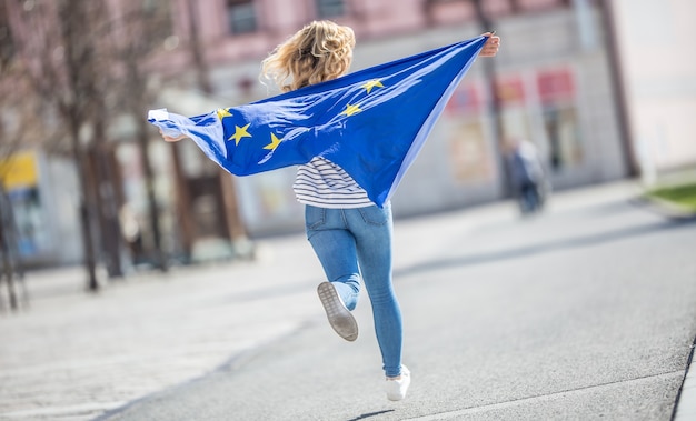 Attraktives glückliches junges Mädchen mit der Flagge der Europäischen Union.