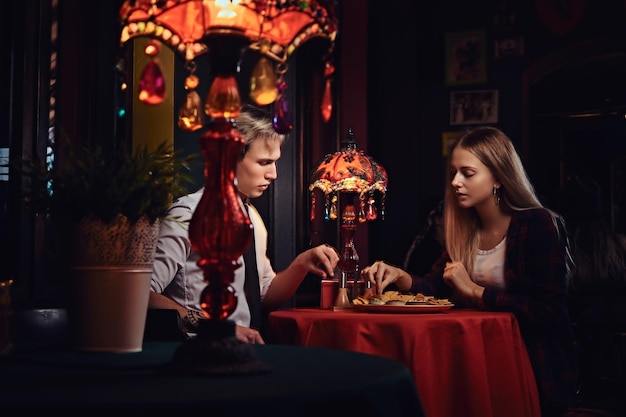 Attraktives junges Paar, das beim Dating im mexikanischen Restaurant Nachos isst.