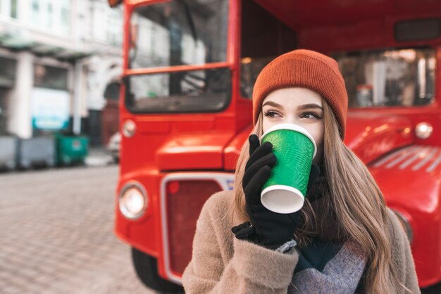 Attraktives Mädchen, das an einem Frühlingstag geht und Kaffee trinkt