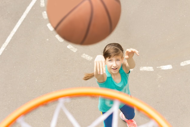 Attraktives Mädchen, das einen Basketball schießt