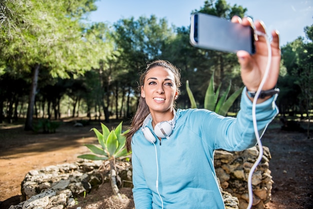 Attraktives Mädchen, das nach ihrem Training im Park ein Selfie macht