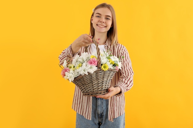 Attraktives Mädchen mit Blumenkorb auf gelbem Hintergrund