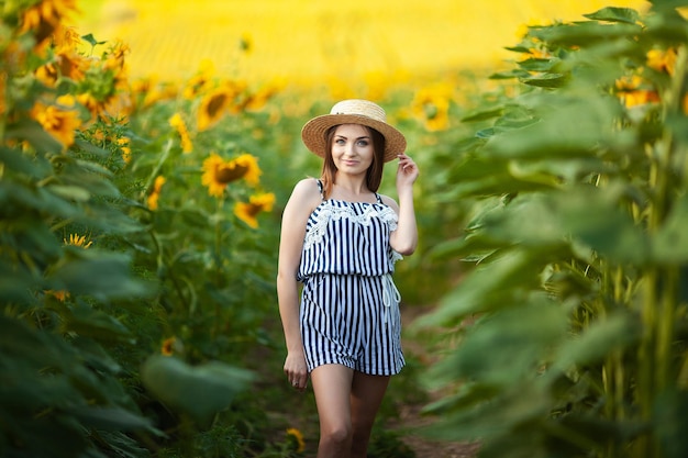 Attraktives Modell der jungen Frau, das im Bereich der Sonnenblumen aufwirft