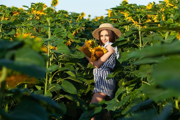 Attraktives Modell der jungen Frau, das im Bereich der Sonnenblumen aufwirft