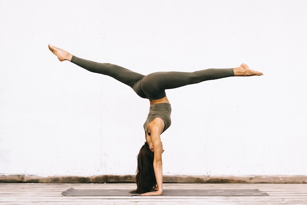 Attraktives Modell in der Yoga-Pose auf weißer Oberfläche in der Kleidung