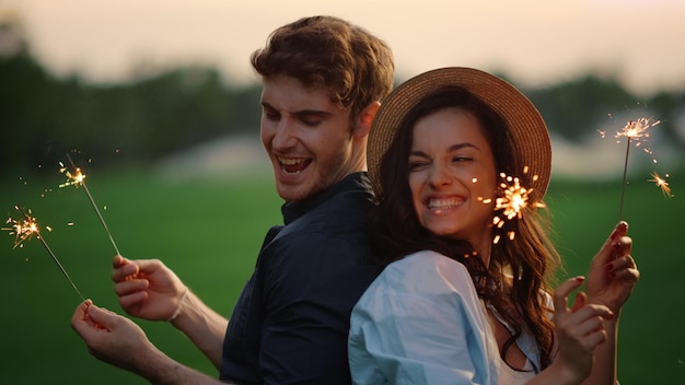 Attraktives Paar bewegt sich mit Lichtern im Park Kerl und Mädchen posieren mit Wunderkerzen