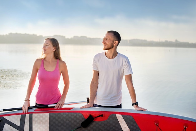 Attraktives Paar, das mit dem Sup-Board-Konzept des aktiven Lebens steht