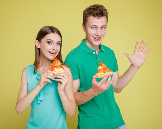 attraktives paar von mann und frau in aquablauem kleid, polo, lächelnd, während sie pizza aus einer schachtel essen