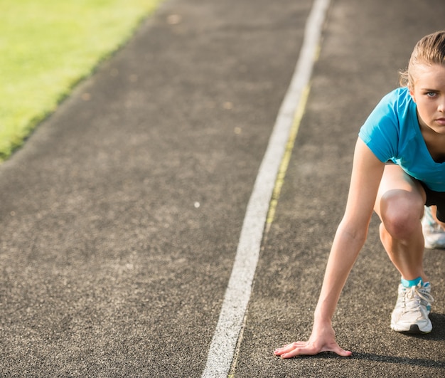 Attraktives sportliches Mädchen bereit, Sprint laufen zu lassen.