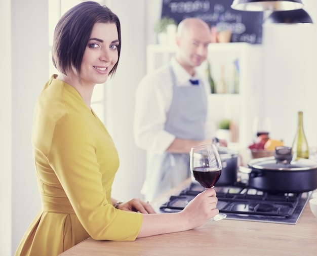 Attraktives verliebtes Paar kocht und öffnet den Wein in der Küche, während sie das Abendessen für einen romantischen Abend zubereiten