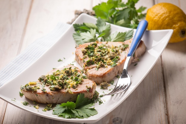 Atún a la plancha con enfoque selectivo de alcaparras y cáscara de limón