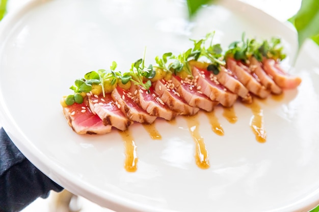 Atún en un plato blanco adornado con hierbas frescas