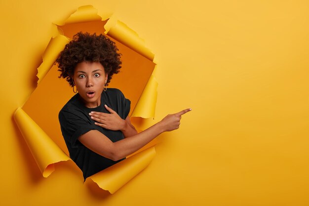 Foto la aturdida mujer afroamericana mira con expresión asustada sin palabras y retiene la respiración de emoción.