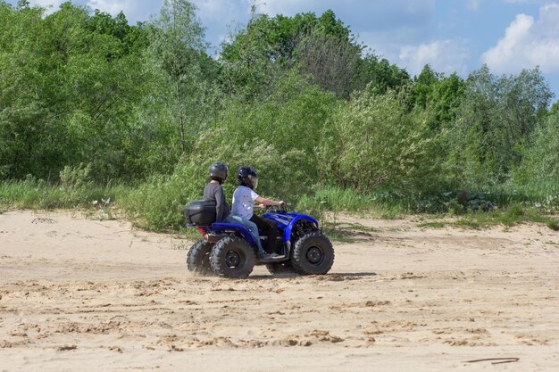 ATV mit Leuten auf dem Sand an der Flussküste s