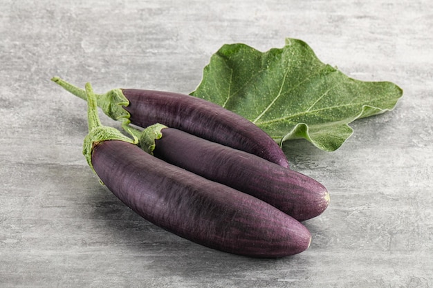 Aubergine púrpura orgânica crua madura com folha