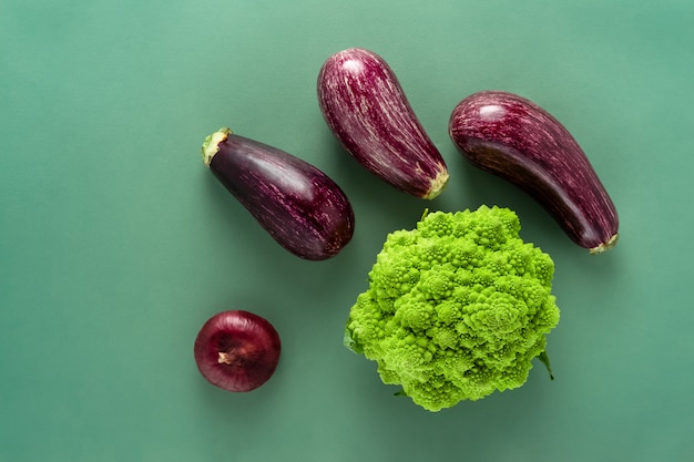 Auberginen und Romanesco-Kohl auf grünem Hintergrund