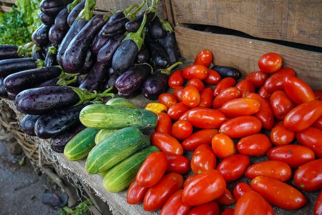 Foto aubergines ou berinjelas, pepinos e tomates ovais em exposição em um mercado de rua na áfrica. detalhe em close-up