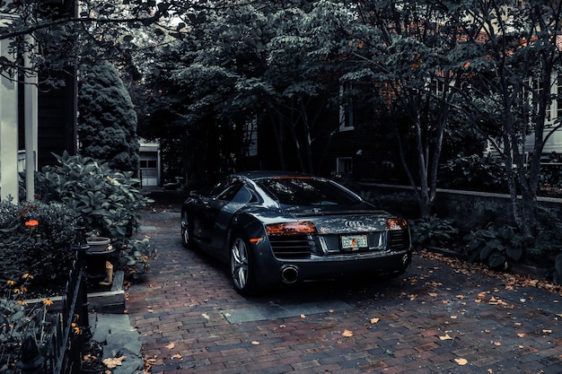 Un audi r8 negro está estacionado en un camino de entrada con una placa que dice audi.