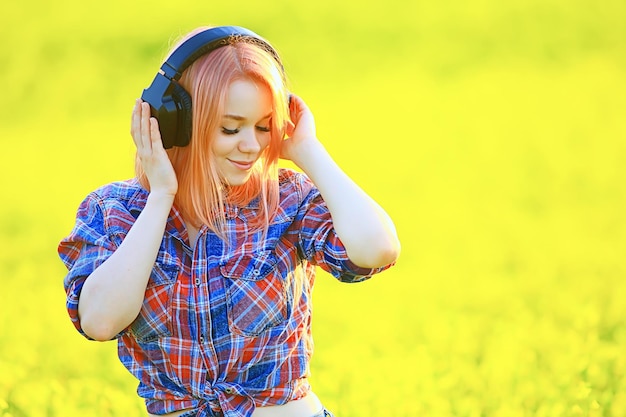 Foto audio-kopfhörer sommer mädchenmusik in einem feld von blumen, junge weibliche frühling