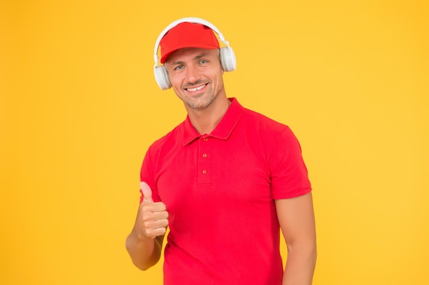 Foto audioguía hombre escucha música auriculares llamada entrante trabajador en uniforme con auriculares hombre en auriculares sobre fondo amarillo asistente del centro de llamadas ayuda a encontrar una solución trabajador de servicio de llamadas de guy