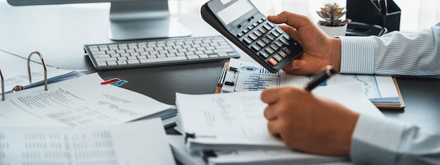 Auditor corporativo que calcula el presupuesto con una calculadora en su escritorio Contador dedicado profesional de la empresa de contabilidad que analiza el documento financiero para pronosticar los ingresos Insight