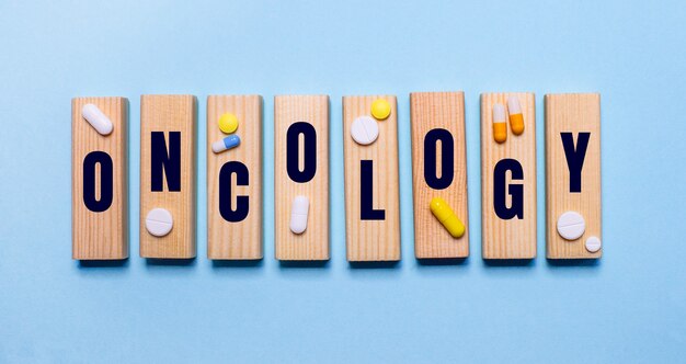 Auf blauem Hintergrund Holzklötze mit Wort ONKOLOGIE und Pillen. Medizinisches Konzept