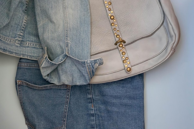 Foto auf blauem hintergrund lässig bequeme damenbekleidung jeans und jeansjacke und tasche