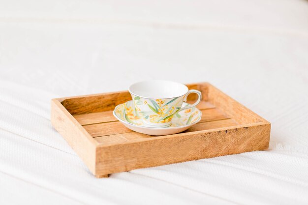 Auf dem Bett steht ein Holztablett mit einer Tasse und Kaffee. Foto