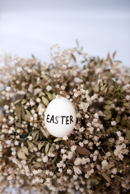 Auf dem Blumenkopierraum liegt ein weißes Ei mit der Aufschrift Ostern