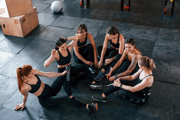 Foto auf dem boden sitzen eine gruppe junger sportlicher menschen hat einen crossfit-tag drinnen im fitnessstudio