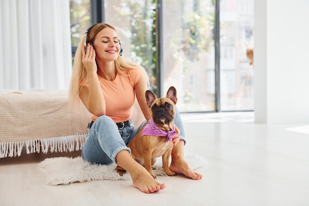 Auf dem Boden sitzend Frau mit Pug-Hund ist tagsüber zu Hause