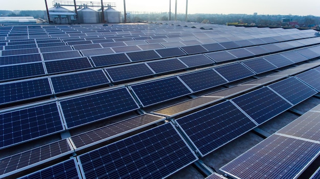 Auf dem Dach des Gebäudes montierte Sonnenkollektoren zur Erzeugung von sauberem ökologischem Strom Große Zisternen und wenige Ingenieure im Hintergrund Dorflandschaft am Horizont