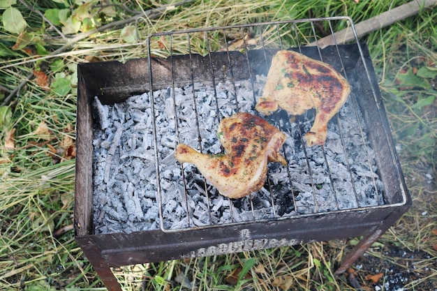 Auf dem Grill werden zwei Hähnchenschenkel gebraten