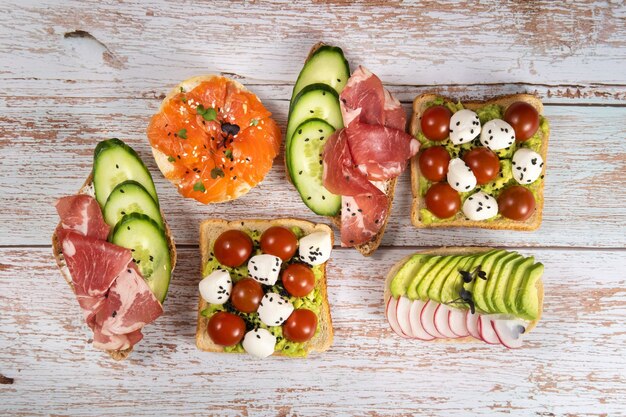 Foto auf dem holztisch lag eine auswahl an sandwiches mit fisch, käse, fleisch und gemüse