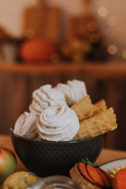 Auf dem Küchentisch steht ein Teller mit Marshmallows und hausgemachten Waffeln. Foto in hoher Qualität