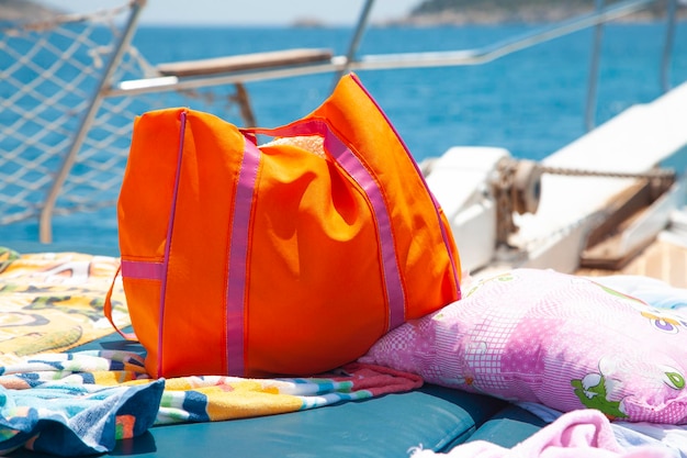 Auf dem Meer sind Urlaubskleidung und orangefarbene Taschen auf dem Boot. Orange und weiße Urlaubstasche.