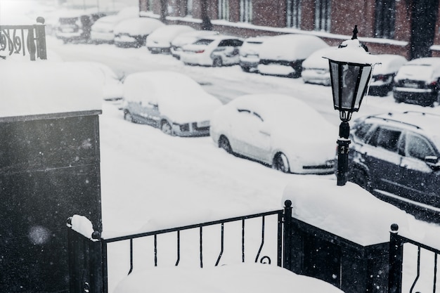 Auf dem Parkplatz stehen schneebedeckte Autos, die wegen schlechten Wetters gelähmt sind