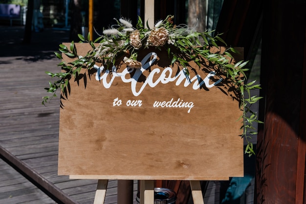 Auf dem Rasen stehende Tafel mit Hochzeitsaufschrift Willkommen zu unserem Hochzeitsmodell