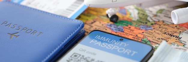 Auf dem Smartphone-Bildschirm Immunitätszertifikat gegen Covid-Flugticket und Reisepass auf dem Tisch