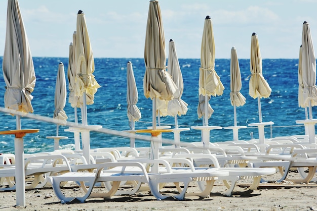 Auf dem Strand gegen den Himmel gebundene Sonnenschirme mit Sesseln