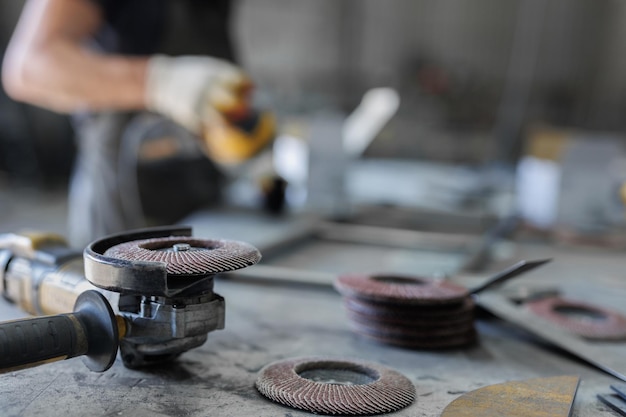 Auf dem Tisch in der Werkstatt steht das Polieren von Metall mit einer manuellen Schleifmaschine mit Polierscheibe