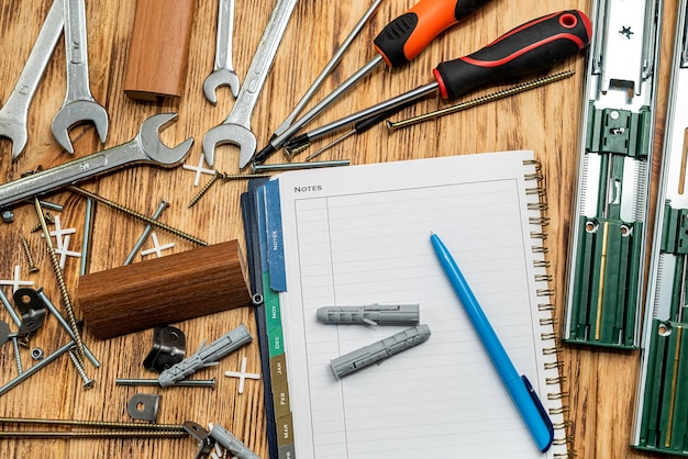 Auf dem Tisch liegen Dübel und Schlüssel verstreut neben einer Mappe und einem Stift