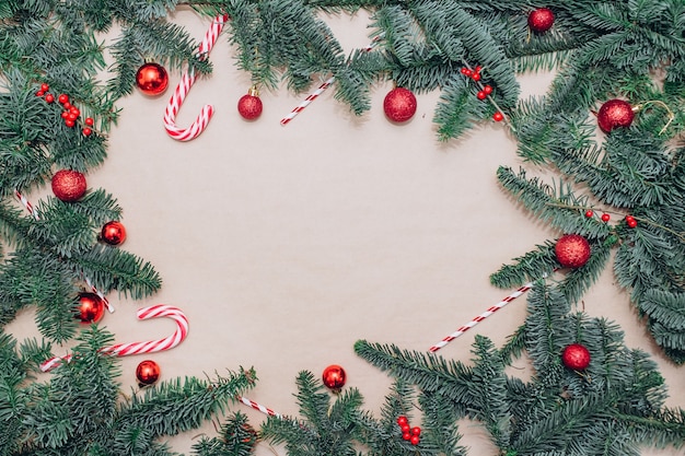 Auf dem Tisch liegen rote Weihnachtskugeln, Tannenzweige, eine Girlande mit Zwiebeln