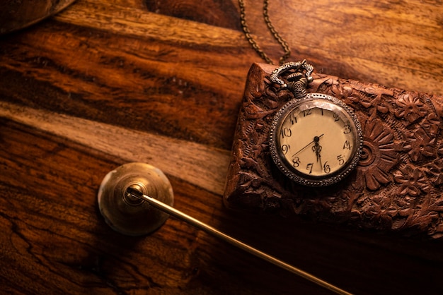 Foto auf dem tisch steht eine alte taschenuhr über einem alten holzgehäuse. vintage hintergrund aus einer sammlung von antiquitäten. nahaufnahme und ausgewählter fokus