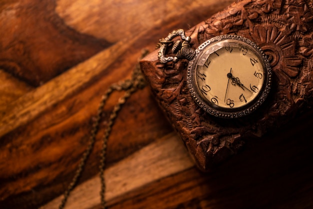 Auf dem Tisch steht eine alte Taschenuhr über einem alten Holzgehäuse. Vintage Hintergrund aus einer Sammlung von Antiquitäten. Nahaufnahme und ausgewählter Fokus