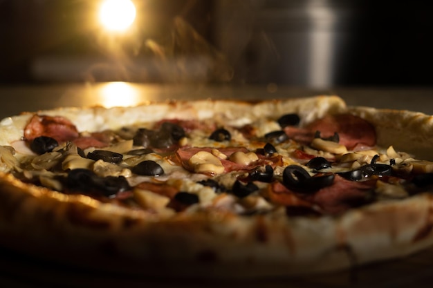 Auf dem Tisch steht eine heiße Pizza mit Mozzarella, darüber steigt Dampf auf. Pizzeria. Lebensmittellieferservice.