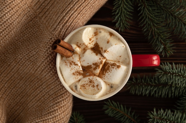 Auf dem Tisch steht eine Tasse heiße Schokolade mit Marshmallows mit Weihnachtsdekoration