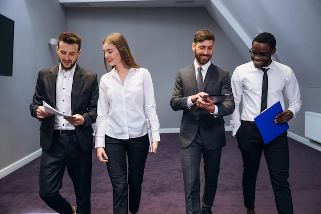 Auf dem Weg zu einem Geschäftstreffen Junge moderne Menschen in vollem Wachstum in eleganter Freizeitkleidung diskutieren, während sie durch das Büro gehen